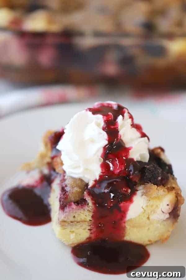 Overnight French Toast Bake with cream cheese and berry syrup on a plate.