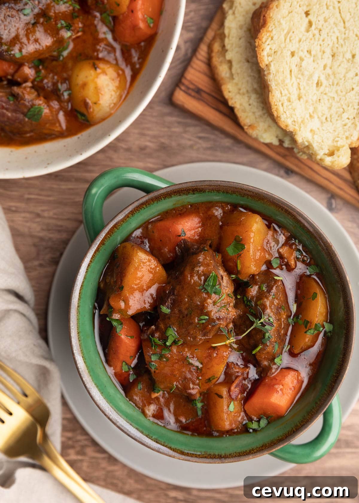 overhead photo of Guinness beef stew with root vegetables in a green double handled crock