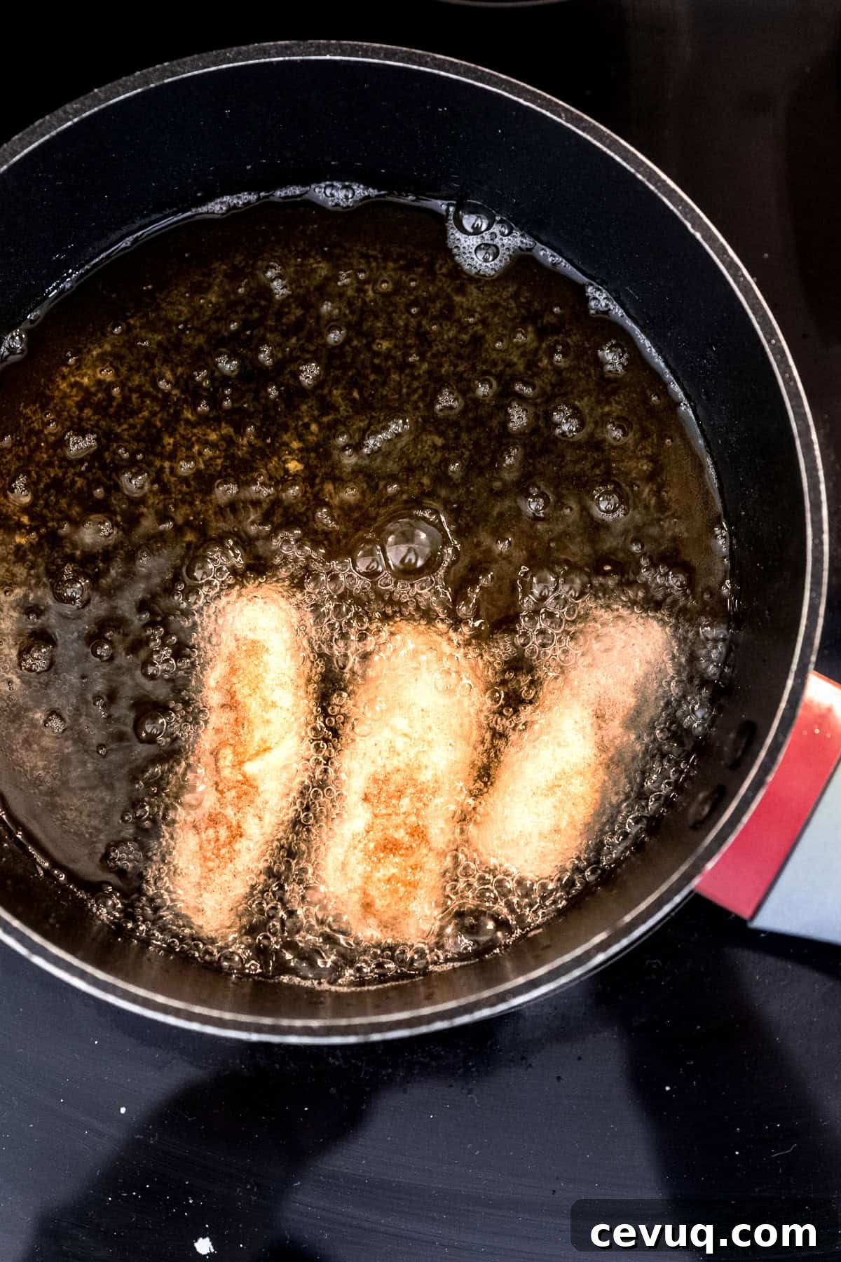 Crispy Homemade Egg Rolls: Step-by-Step Recipe for Perfect Rolls 8 Homemade egg rolls frying in oil on the stove.