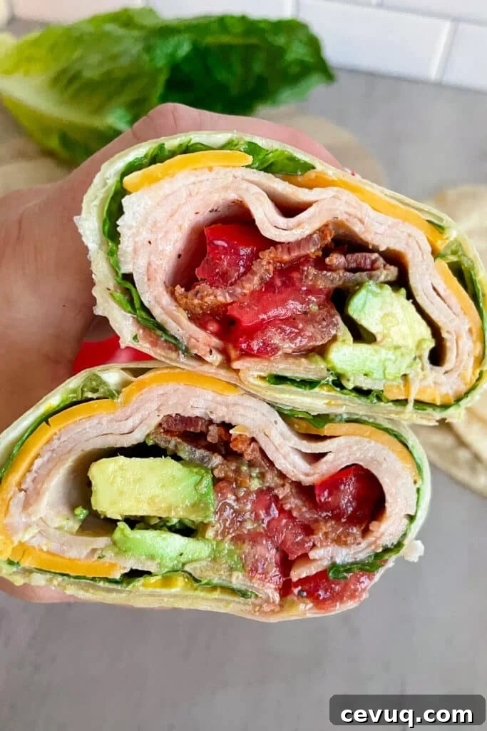 Easy Turkey Bacon Club Wrap (With Avocado) stacked on top of each other and held in my hand