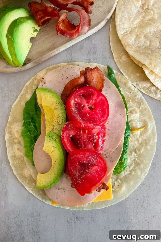 how to make a turkey bacon club wrap with tortilla, lettuce, turkey, cheese, tomato, and avocado
