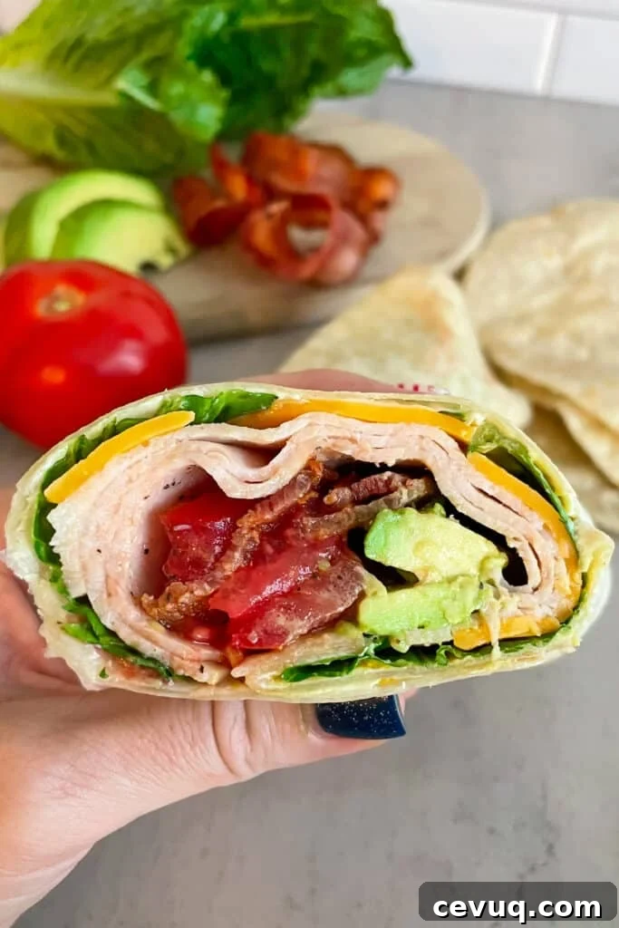 turkey club wrap held in my hand showing what the inside of the wrap looks like when made