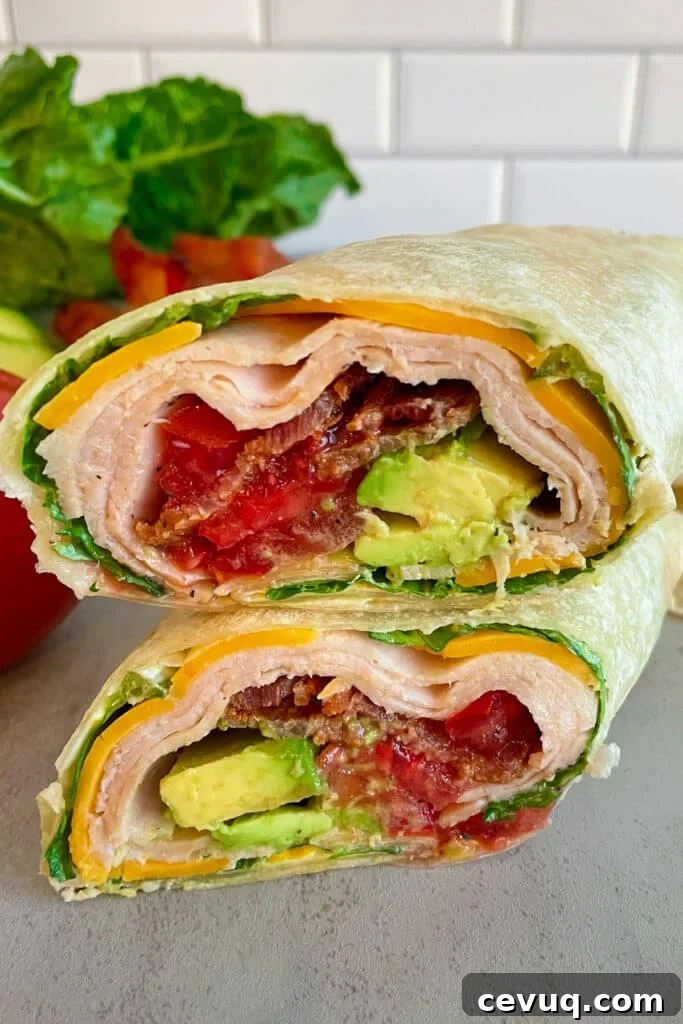 turkey club wrap made and cut in half, stacked on top of each other to show the inside of the wrap