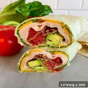 turkey club wrap made and cut in half, stacked on top of each other to show the inside of the wrap