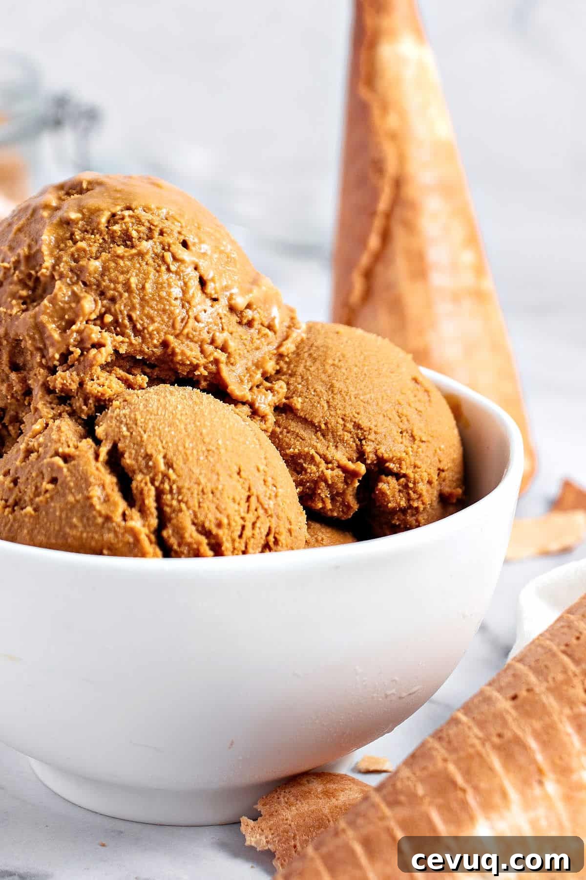 Gray background, white bowl with brown sugar ice cream scoops. Waffle cones.
