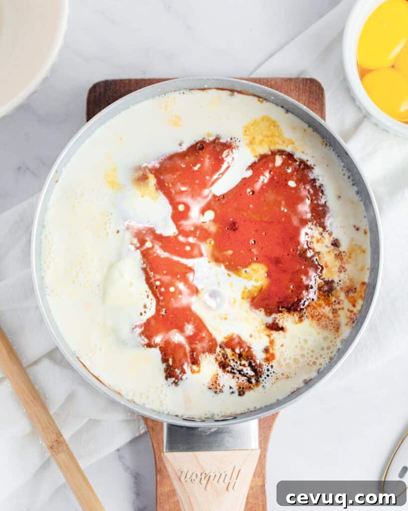Cream and milk added to caramel mixture in a skillet. Gray background. Top view.