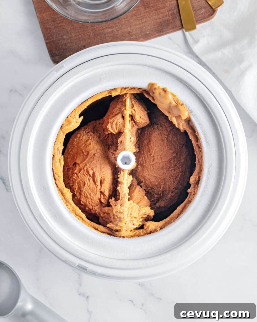 Ice cream machine bowl with churned brown sugar ice cream. Top view. Light gray background.