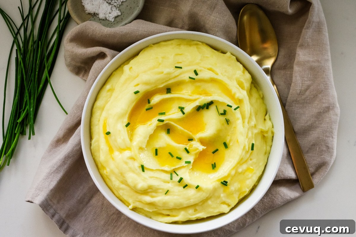 Mashed potatoes in a white bowl with a spoon beside it.