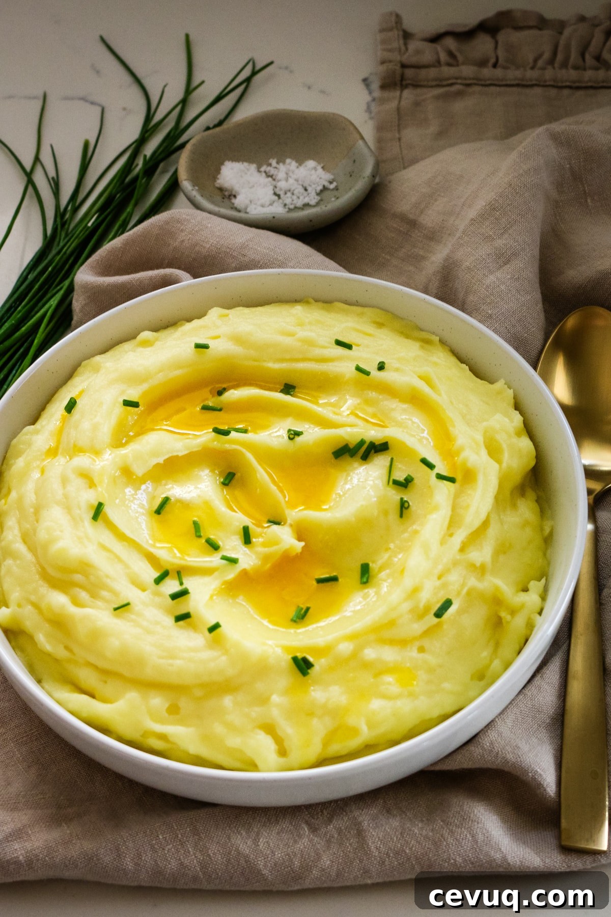 Mashed potatoes in a white bowl with a spoon beside it.