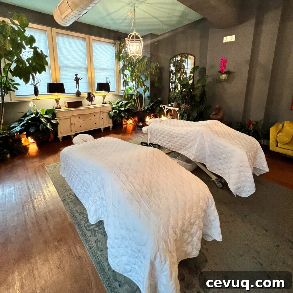 A cozy spa room with two massage tables, soft lighting, and plants.