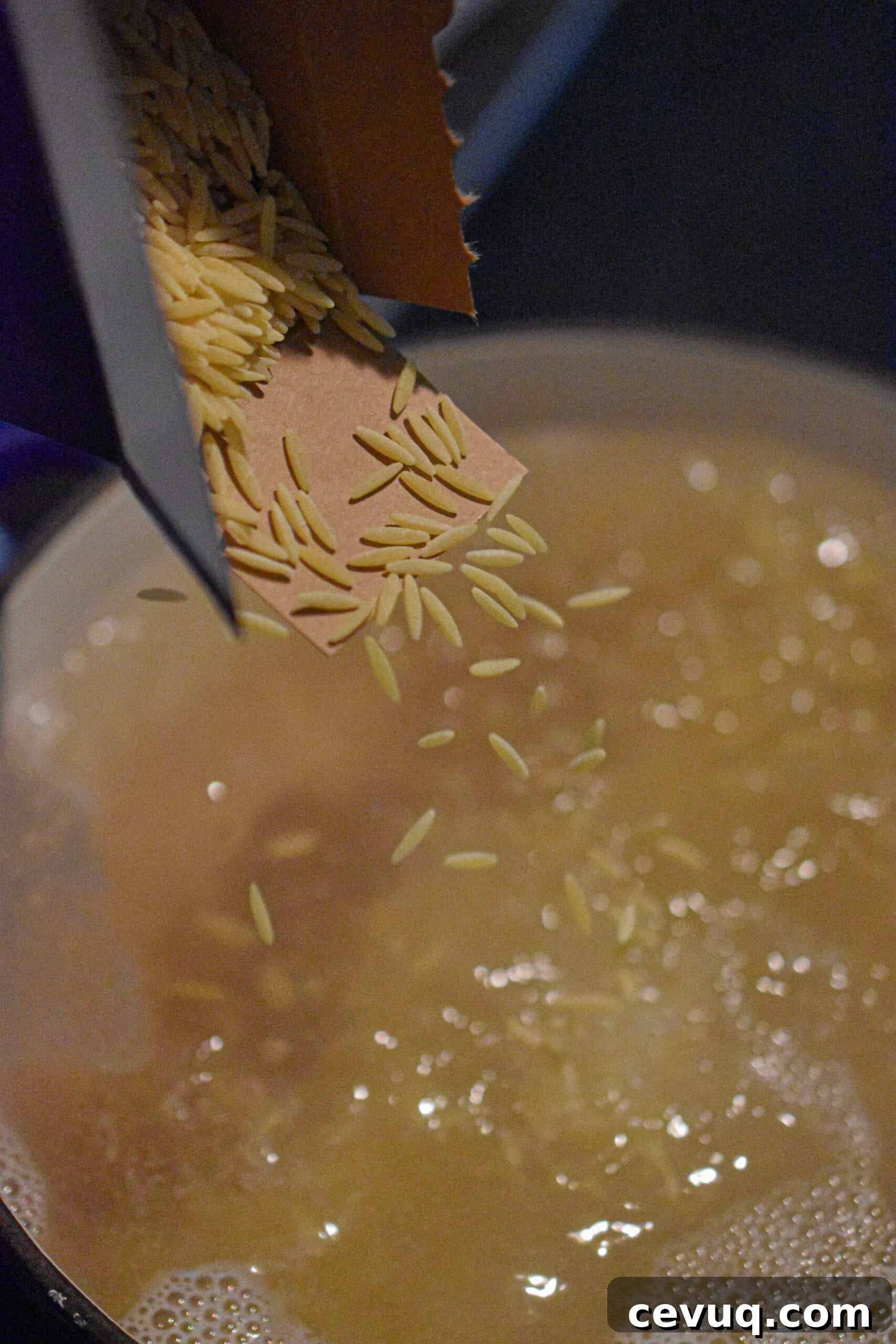 Orzo being dropped into a pot of boiling water