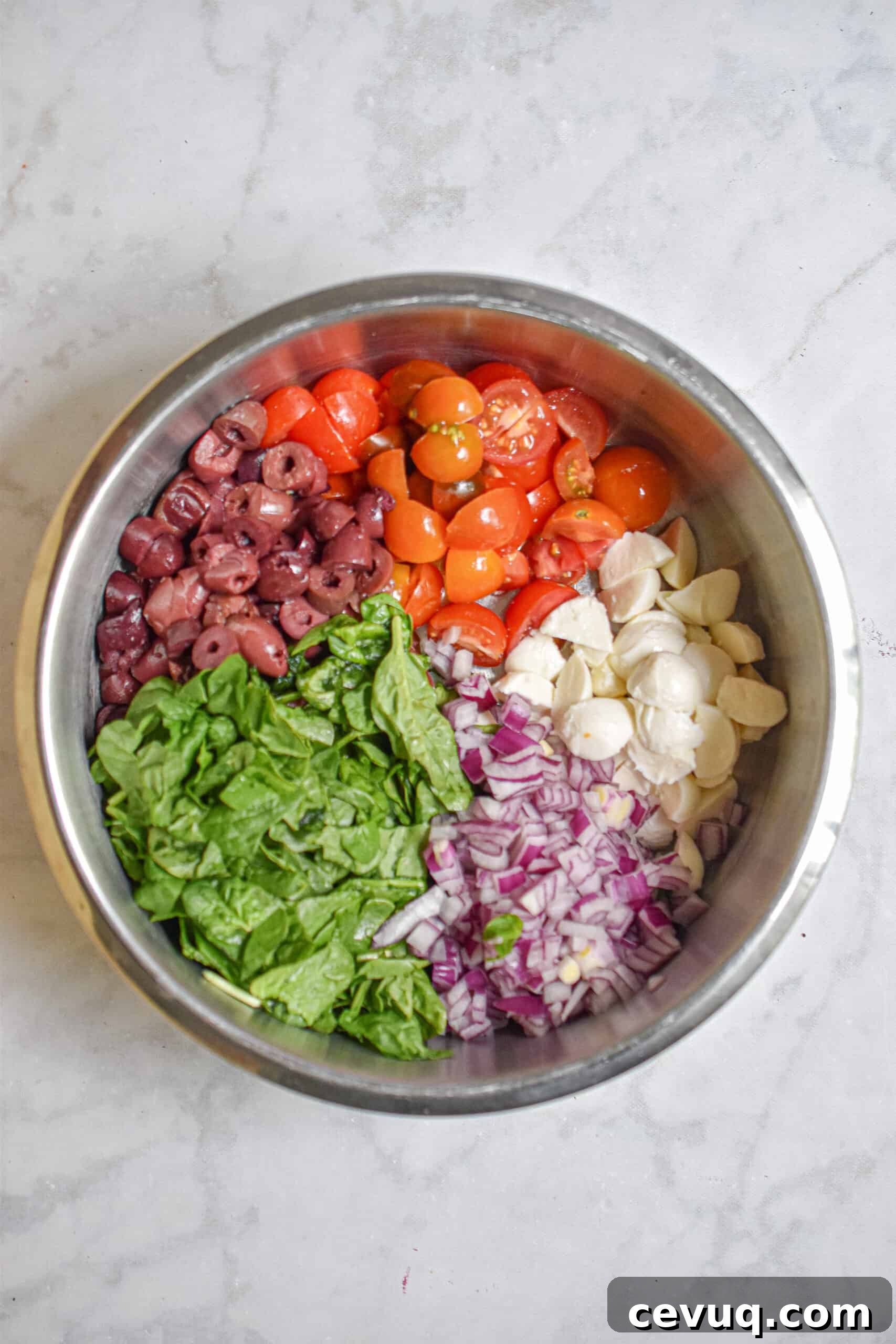 The fresh mozzarella, tomatoes, olives, onions, and spinach in a bowl
