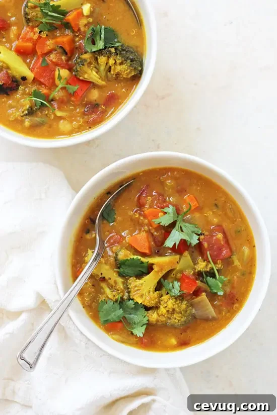 Two bowls of Turmeric Quinoa Vegetable Soup with a spoon and white napkin.