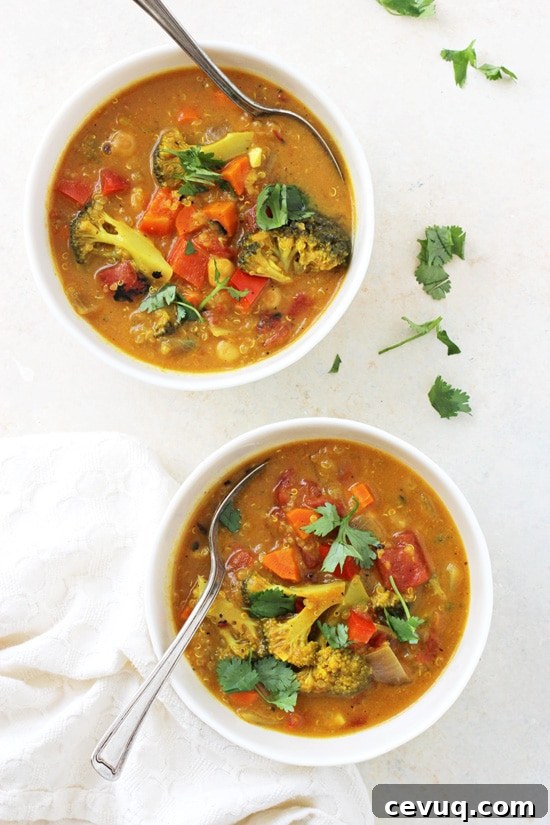 An overhead view of two bowls of Turmeric Quinoa Vegetable Soup with two spoons.