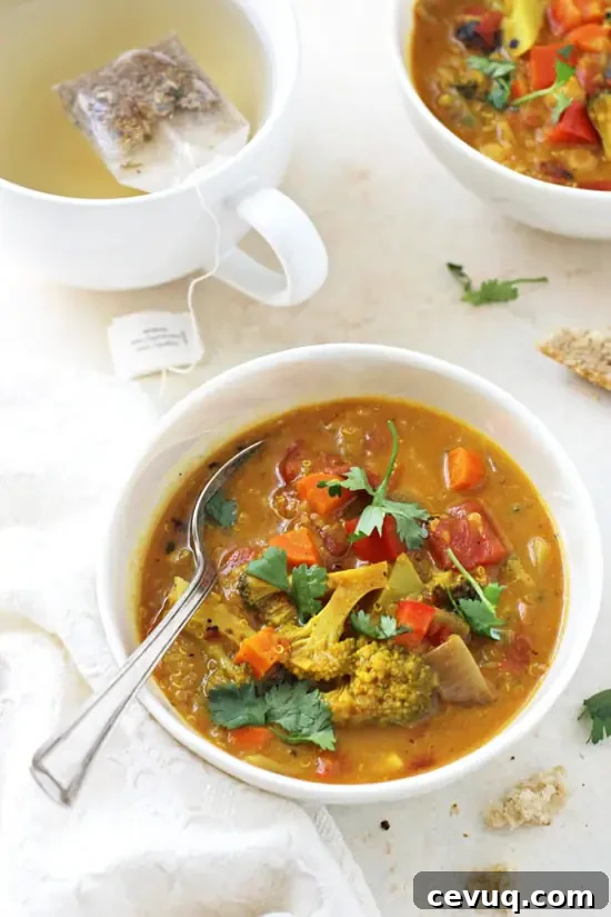 Side angle view of two bowls of Turmeric Quinoa Vegetable Soup with a cup of tea.