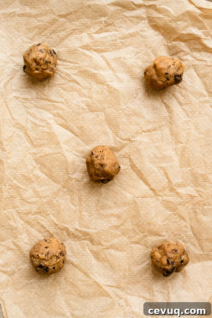 Bakery-Style Chocolate Chip Cookies Recipe for Perfect Texture 11 Five cookie dough balls on a parchment paper lined baking sheet.