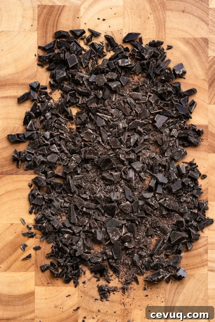 Bakery-Style Chocolate Chip Cookies Recipe for Perfect Texture 4 Dark chocolate bar chopped into pieces on a wood cutting board.