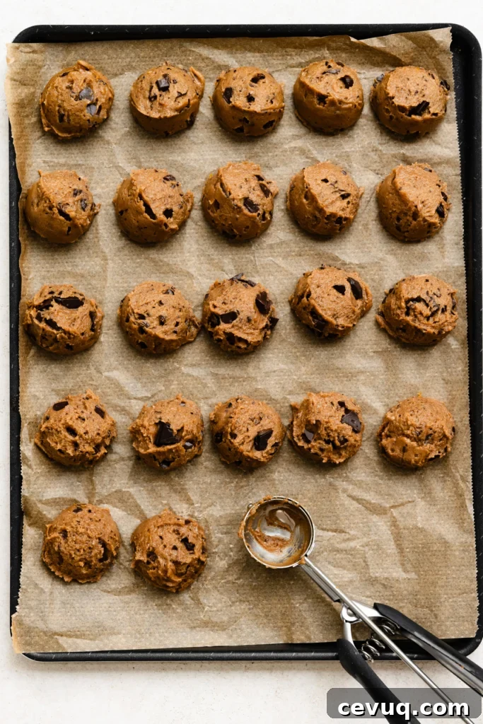 Bakery-Style Chocolate Chip Cookies Recipe for Perfect Texture 10 Overhead view of pre-scooped cookie dough balls on a parchment paper lined baking tray.