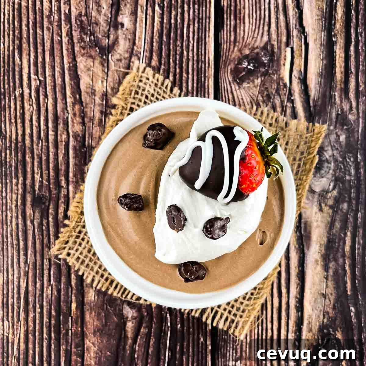 The coffee mousse in a white ramekin, topped with whipped cream, chocolate covered coffee beans, and a chocolate dipped strawberry.