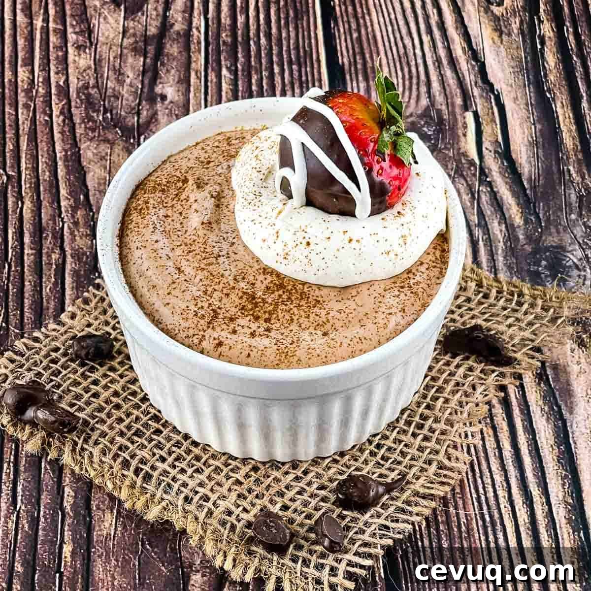 The coffee mousse in a white ramekin, topped with whipped cream, a chocolate covered strawberry, and a sprinkle of espresso powder.