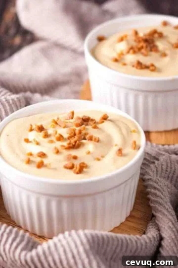 Two white ramekins filled with dulce de leche mousse, garnished with toffee bits.
