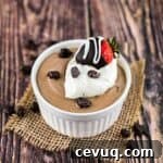 Creamy coffee mousse in a ramekin, topped with a dollop of whipped cream and a chocolate covered strawberry and chocolate covered coffee beans.