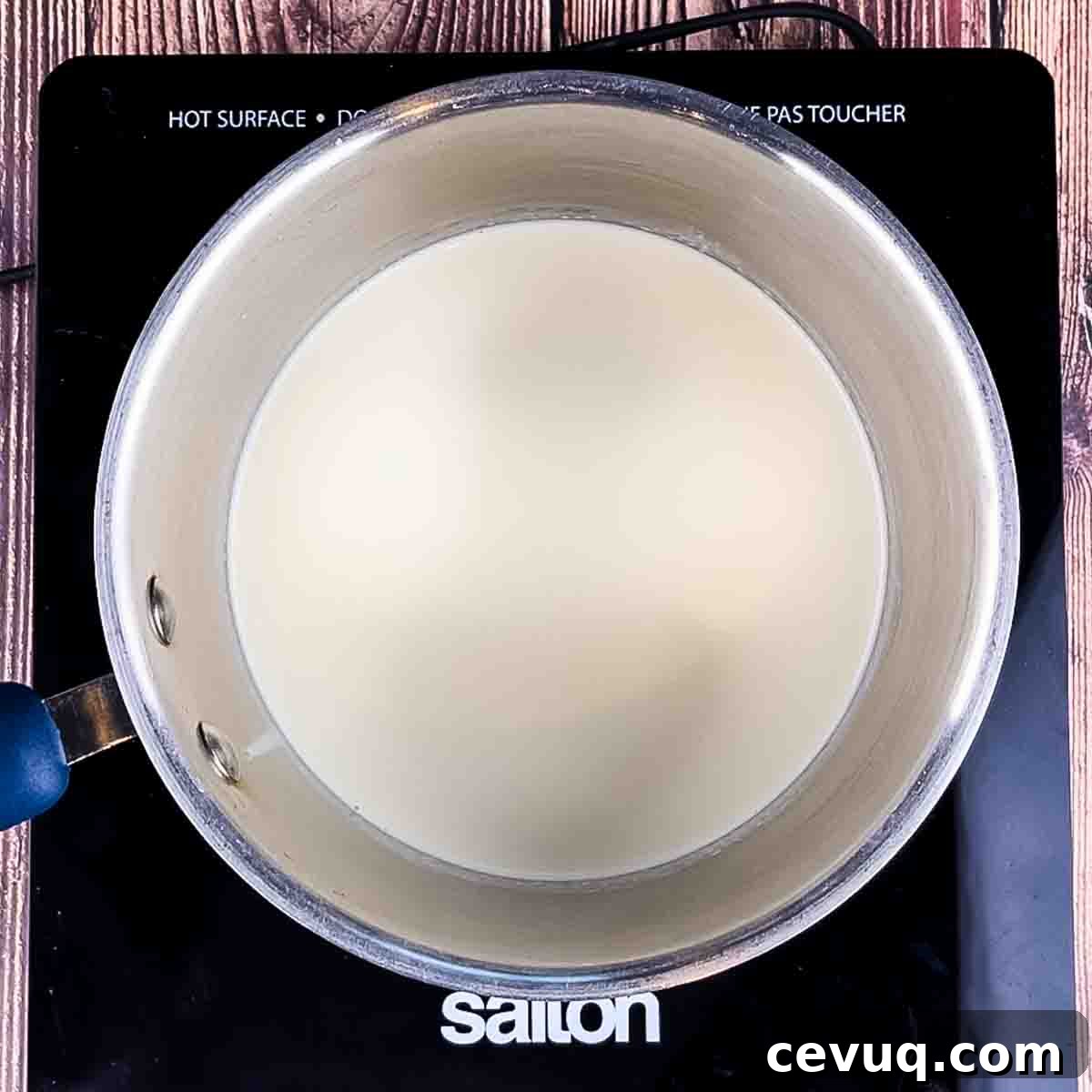 The heavy cream heating in a small saucepan on the stove.