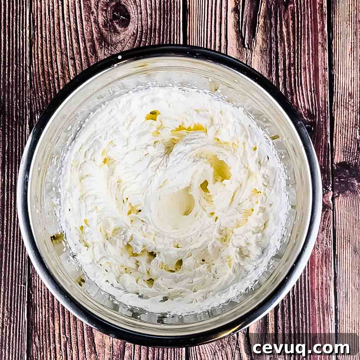 The heavy whipping cream mixed until stiff peaks form in a mixing bowl.