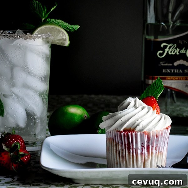 A strawberry mojito cupcake on a plate next to a mojito.