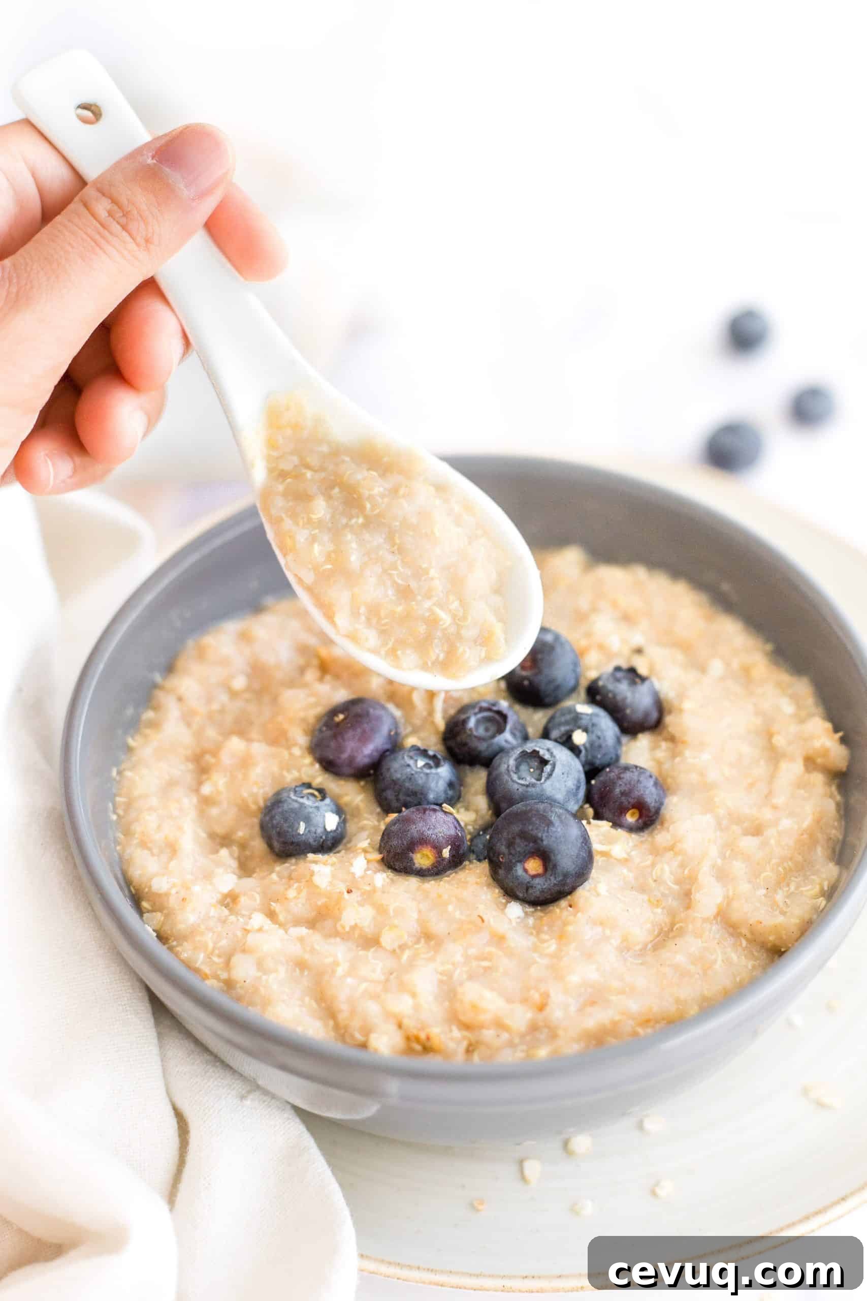 5-Minute Creamy Quinoa Porridge (Gluten-Free, Vegan) Holding up a spoonful of quinoa oatmeal from a bowl.
