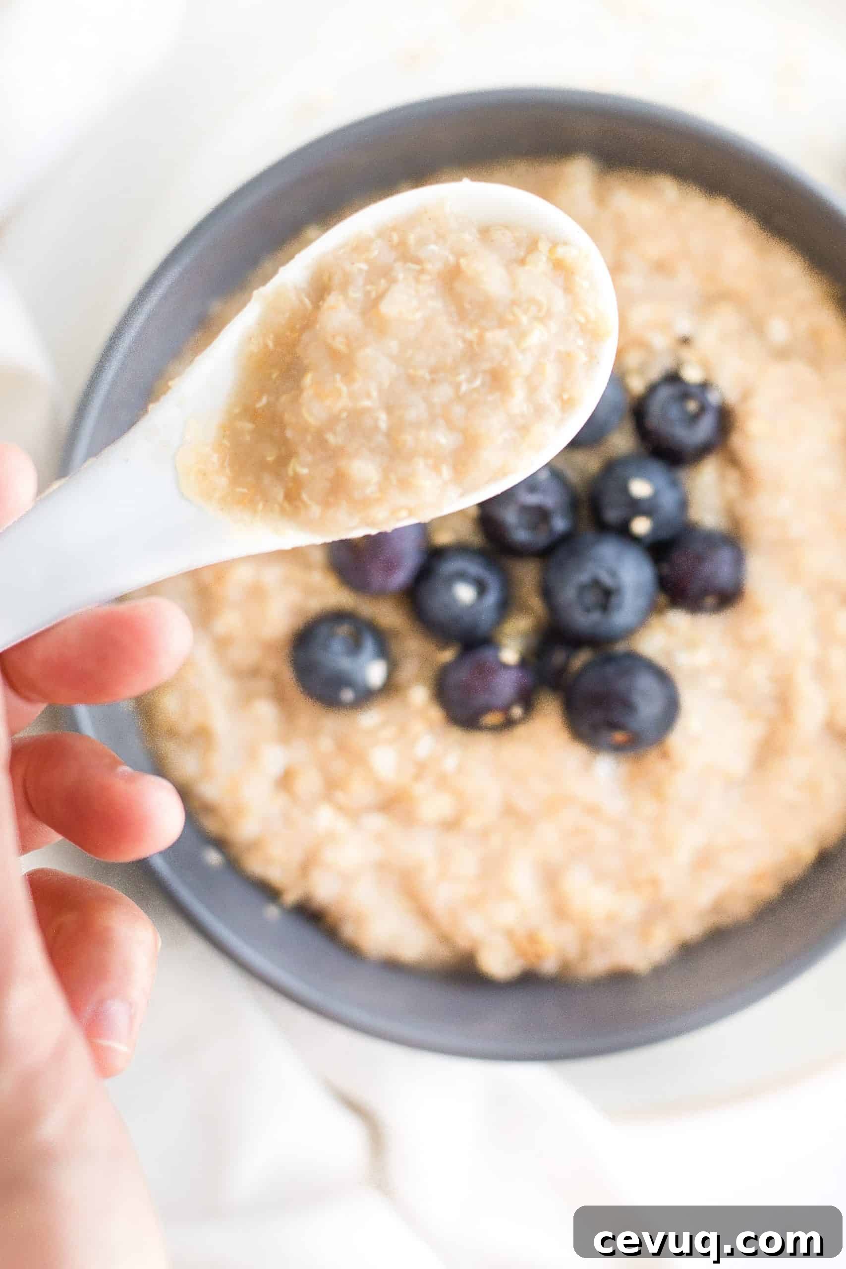 5-Minute Creamy Quinoa Oatmeal Porridge (Gluten-Free, Vegan) Holding up a spoonful of quinoa oatmeal porridge.