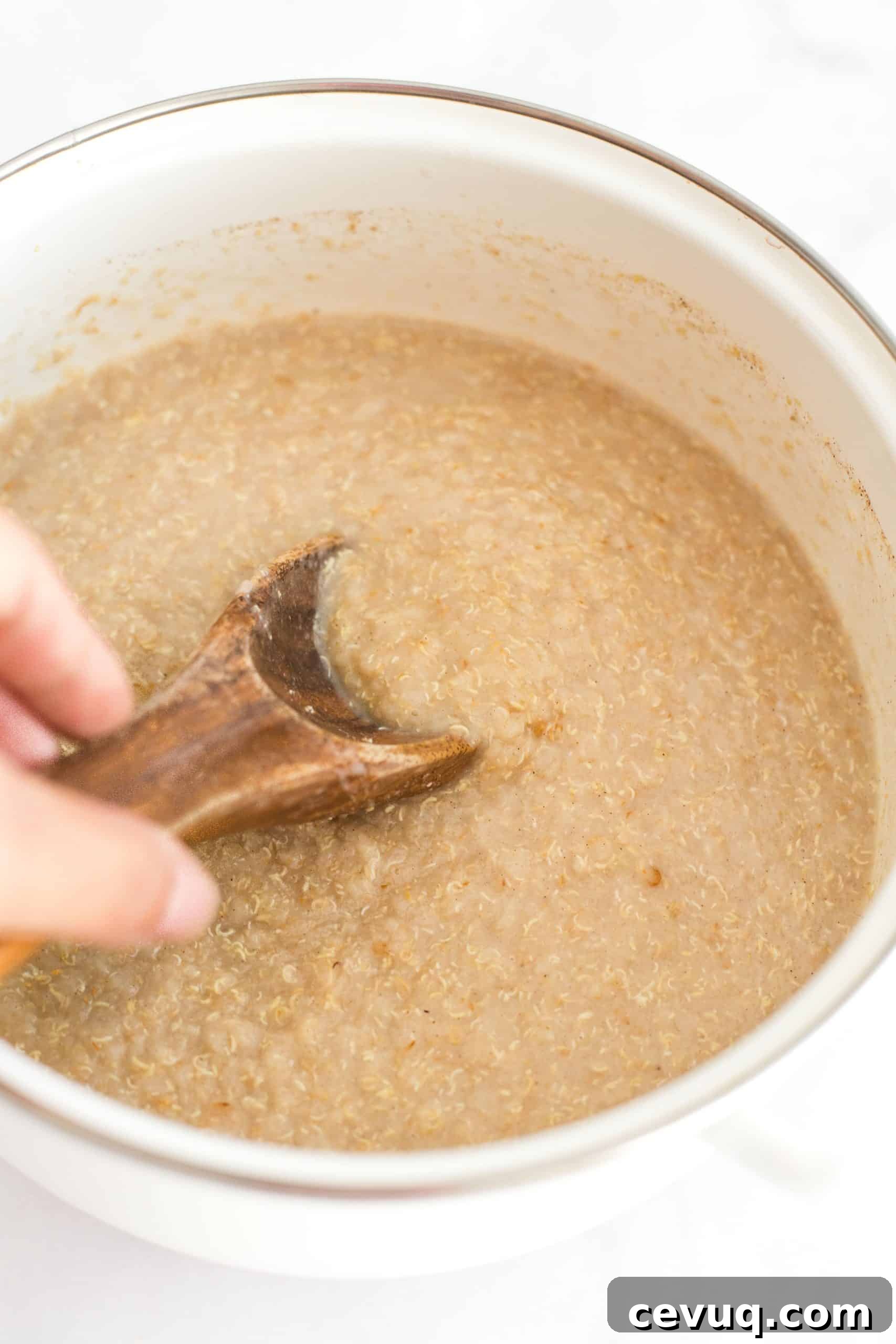 5-Minute Creamy Quinoa Flake Recipe (Gluten-Free, Vegan) Mixing oatmeal porridge in a white pot.