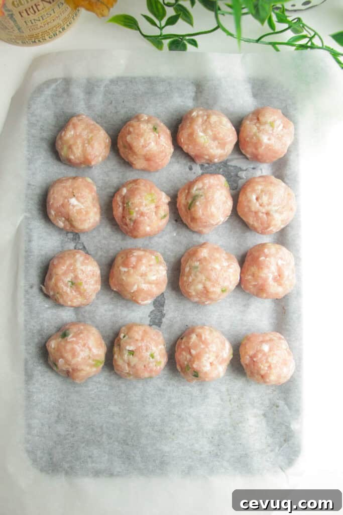 Chicken meatballs on a parchment paper lined oven tray.