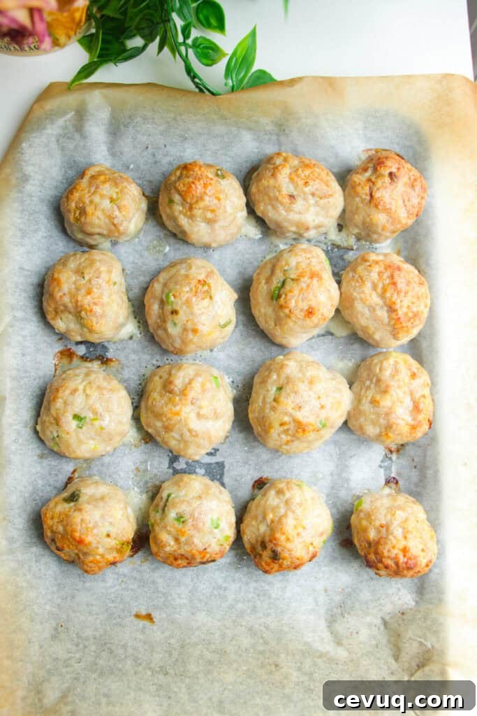 Chicken meatballs baked on a lined oven tray.