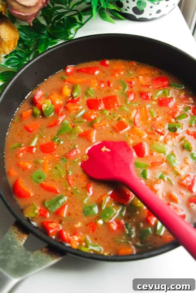 Sauce added to bell peppers in a frying pan.