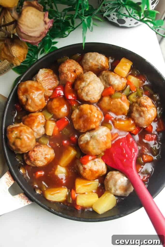 Chicken meatballs added into sweet and sour sauce in a pan.