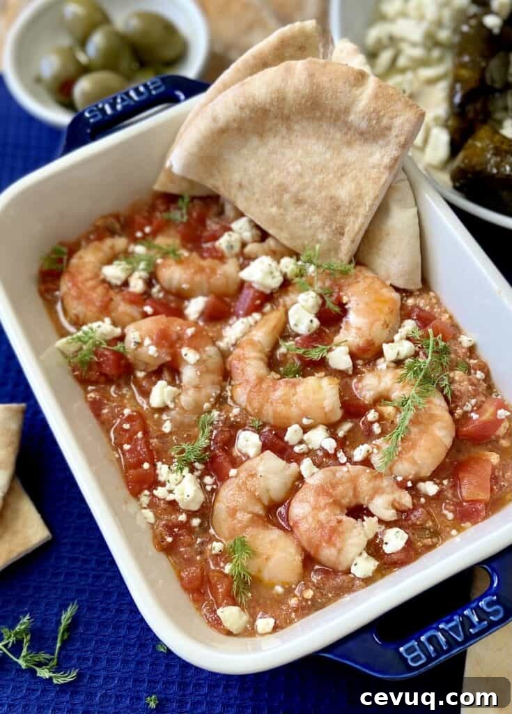 Baked Greek Shrimp in a white baking dish with pita bread on the side.