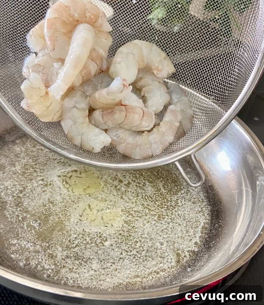 Shrimp being added to saucepan with melted butter.