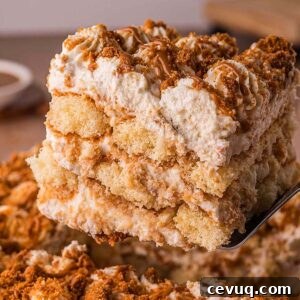 A close-up of a creamy Biscoff Tiramisu slice being lifted from a tray with a spatula, showcasing its luscious layers.