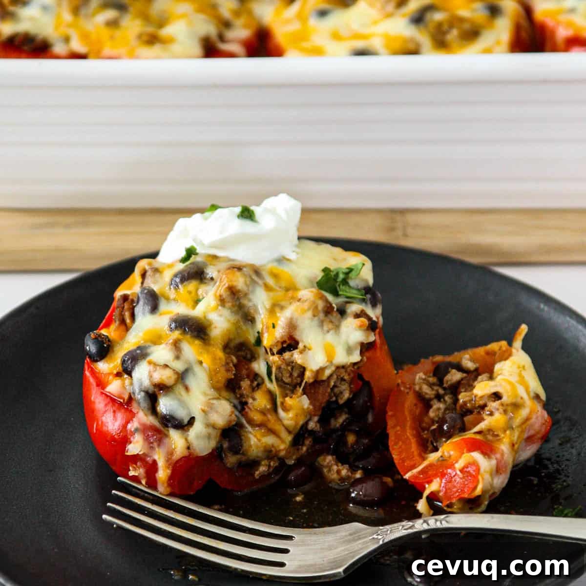 A taco stuffed pepper on a black plate with a silver spoon.