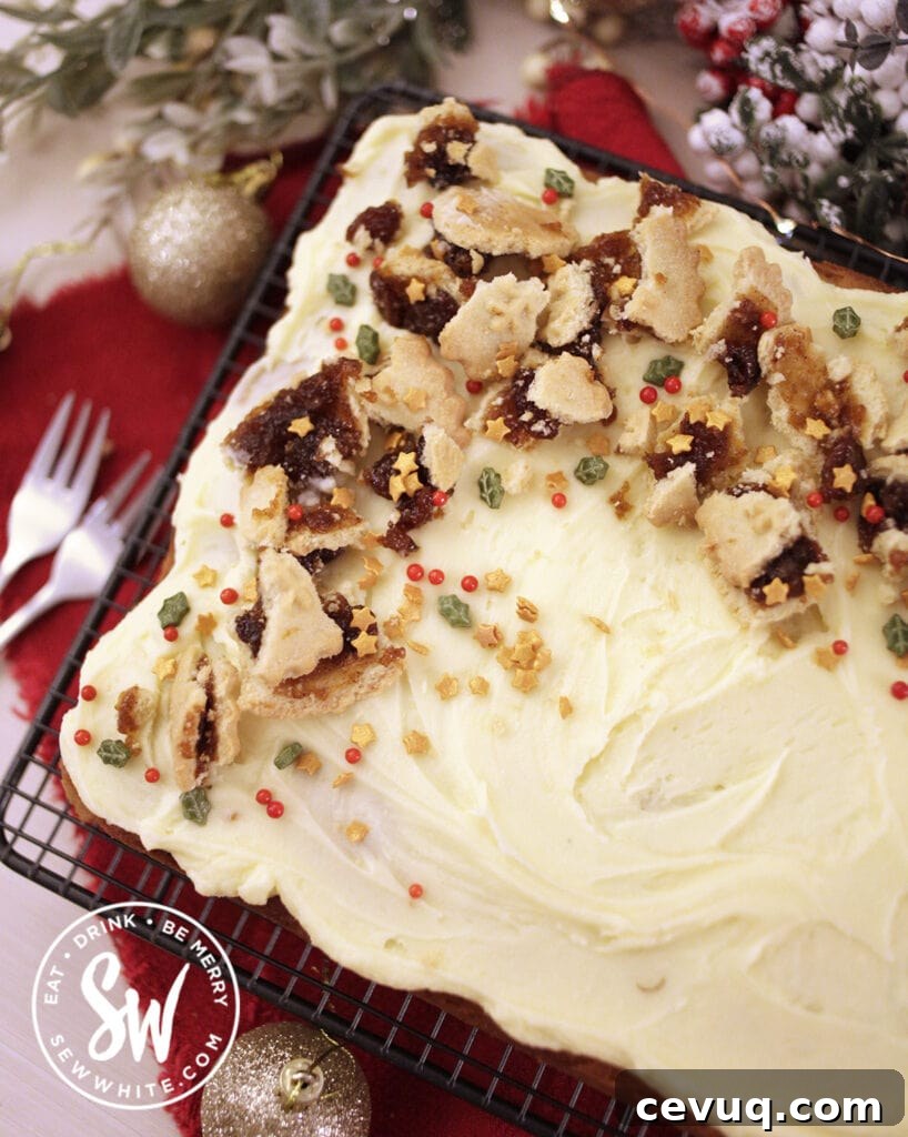 Mincemeat Cake: Festive Mince Pie Layer Cake Recipe 4 Mincemeat Cake topped with broken mince pies and christmas sprinkles on a red blanket with Christmas decorations.