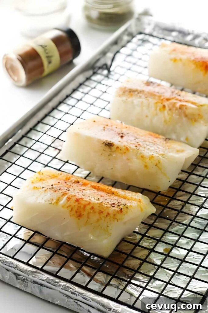 Seasoned cod fillets on a wire rack, ready to bake.
