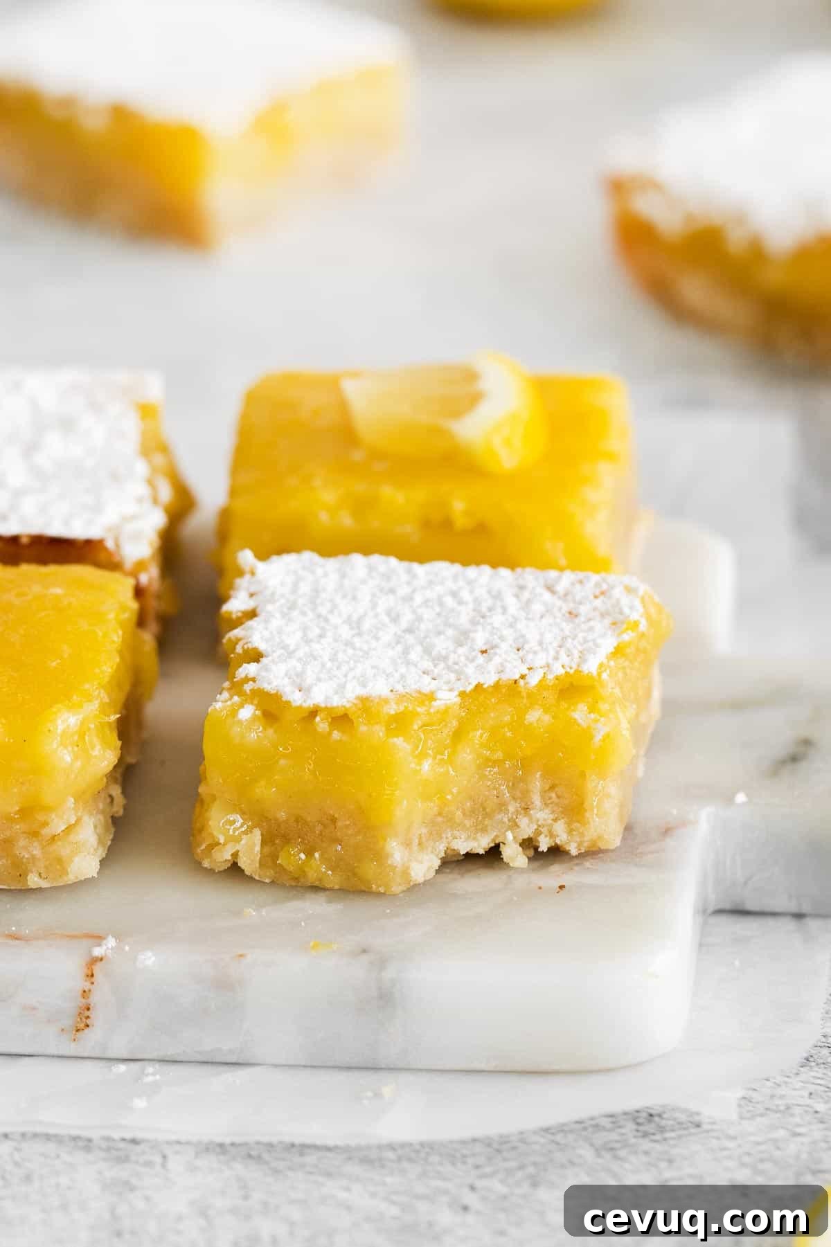 gluten-free lemon bars on a marble platter with one bite missing.