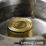 pouring water over a can of sweetened condensed milk in a pot.