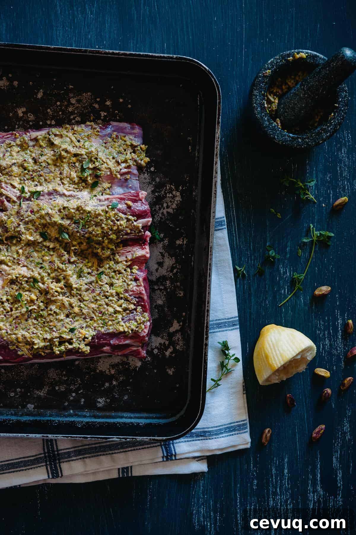 a lamb loin covered in herbs and spices on a baking tray