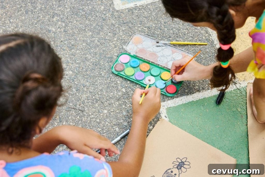 two girls painting on paper outdoors