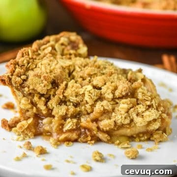 Slice of apple crumb pie on white plate.