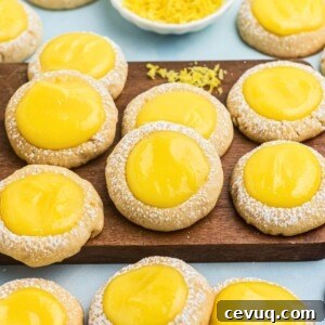Shortbread cookies topped with a spoonful of lemon curd on a small wooden cutting board.