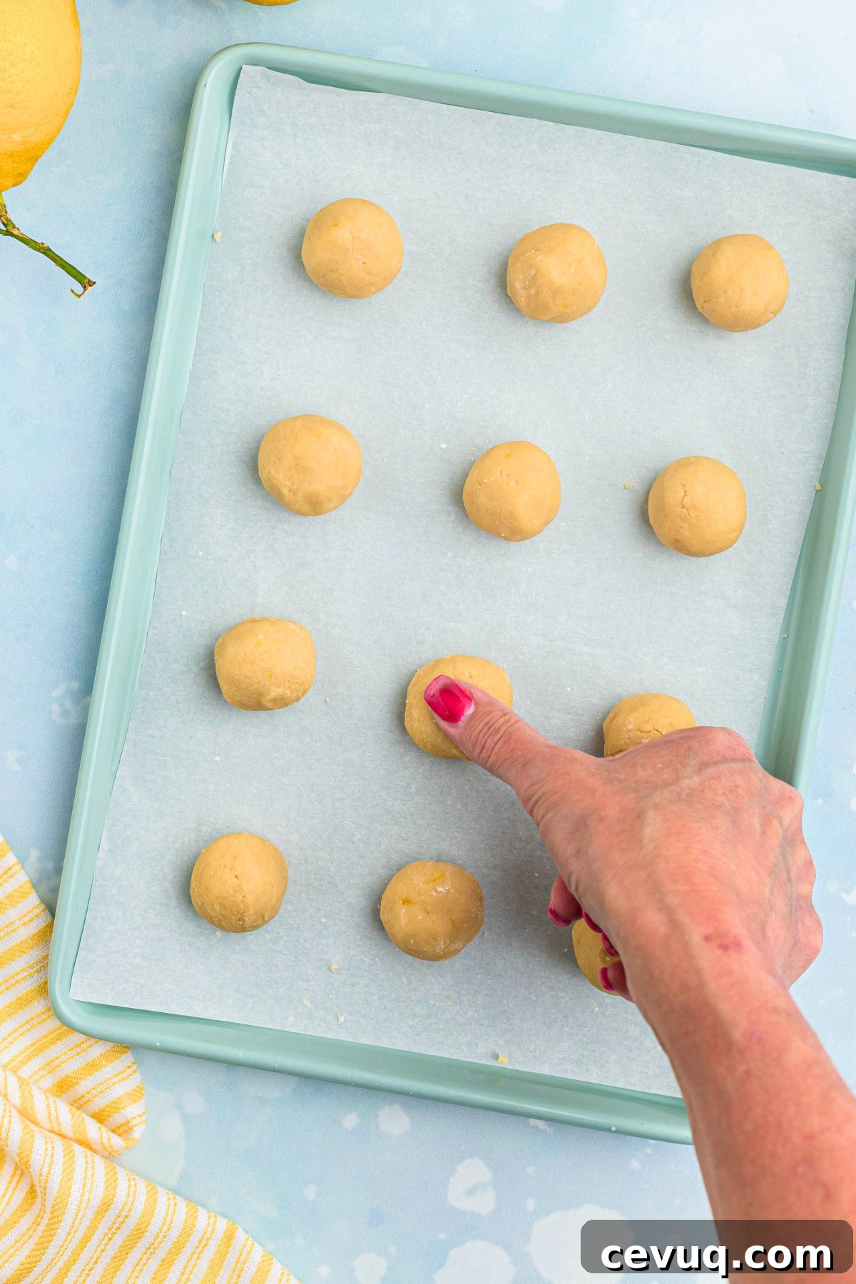 Thumb being used to make indent on top of cookie dough for lemon curd drop. 