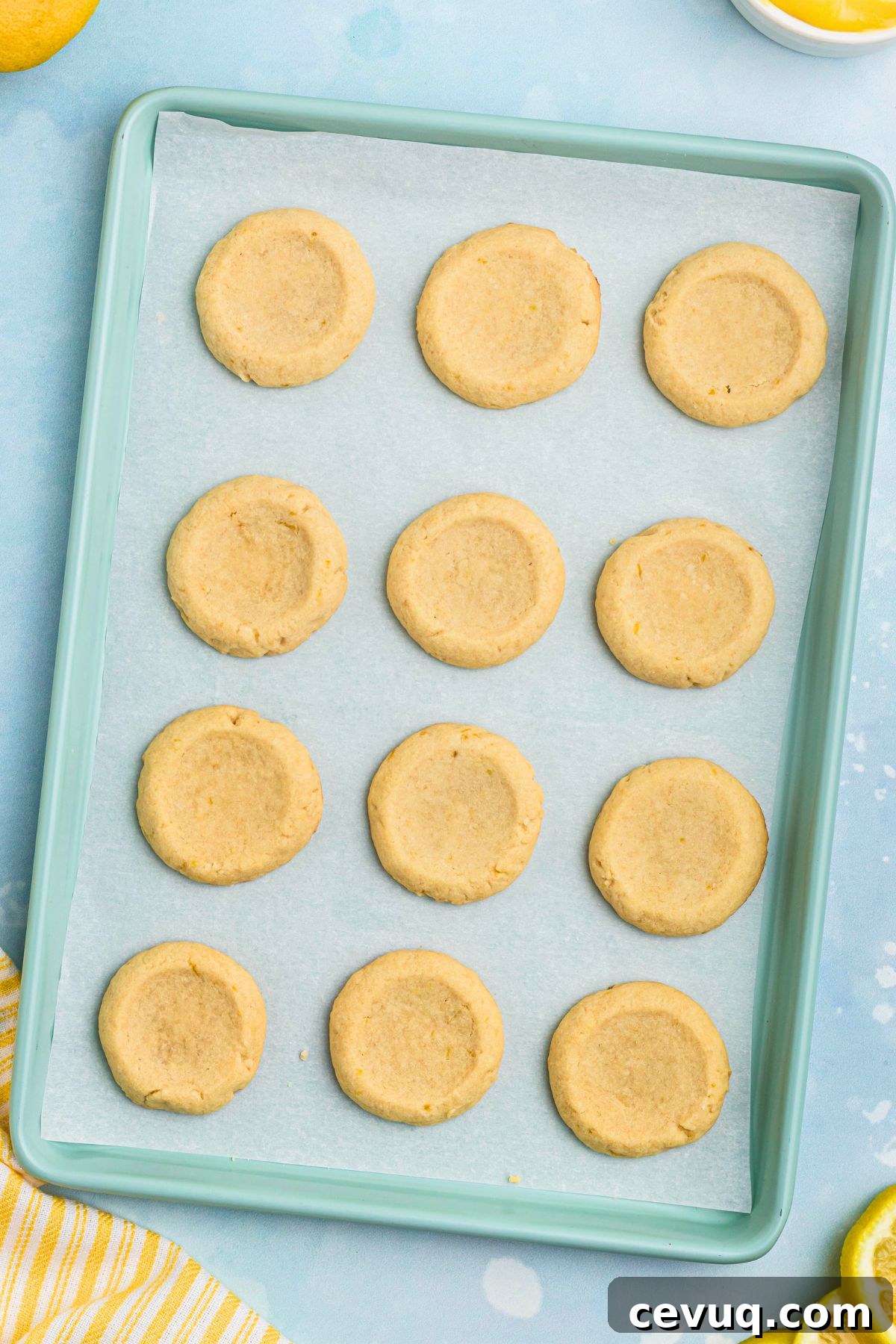 Unbaked cookies with small indentations on baking sheet lined with parchment paper. 